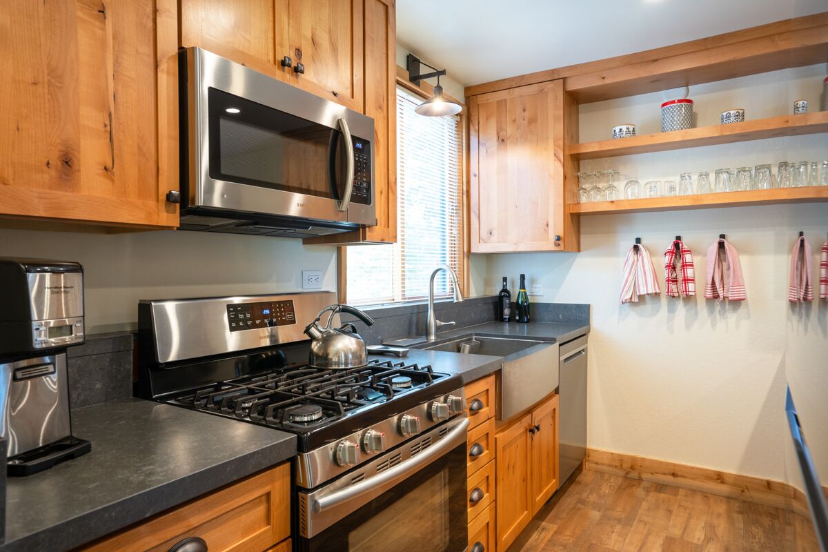 A modern kitchen with wooden cabinets, stainless steel appliances, a gas stove, and a built-in oven.