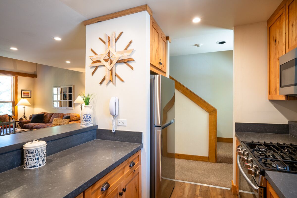 Una cocina moderna con armarios de madera, estufa integrada y un gran elemento decorativo en la pared.