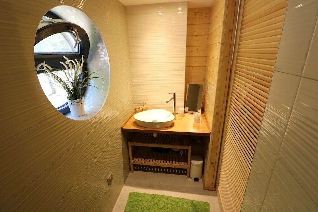 Un baño moderno con un ventanal redondo, un lavamanos y un espejo.
