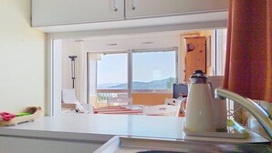 A kitchen with a view of a balcony, a kettle, and a sink. - Quiet studio with terrace in Bormes-les-Mimosas (Bormes-les-Mimosas)