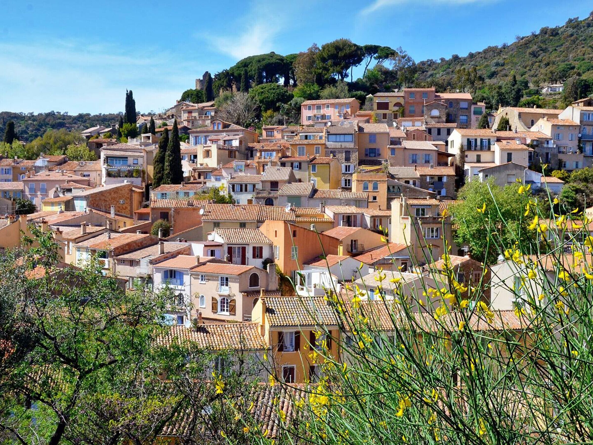 A densely packed hillside town with terracotta-roofed buildings, a prominent church spire, and lush greenery.
