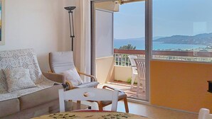 A balcony with a view of the sea and hills, a sofa, a chair, and a table. - Quiet studio with terrace in Bormes-les-Mimosas (Bormes-les-Mimosas)