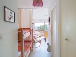 Una habitación con literas, una silla, una mesa y vistas al exterior.