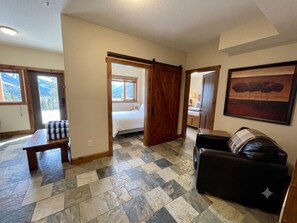 A spacious living area with a checkered floor, a sofa, a bed, and a dining table.