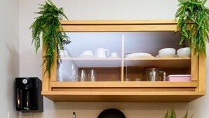 Una cocina con un armario de madera, una cafetera, un lavamanos y una planta en maceta.