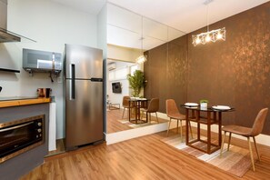 A modern kitchen with a built-in microwave, stainless steel refrigerator, and oven. There is a dining area with a wooden table and chairs. - 1 Minute From Ipanema Beach Vsc3 (Rio de Janeiro)