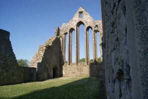 An ancient stone structure with multiple arches and a ruined wall.