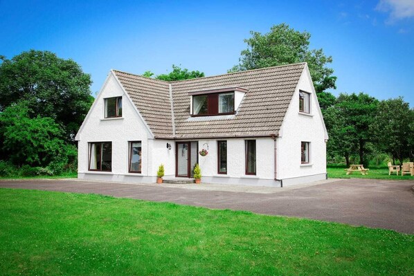 A two-story house with a pitched roof, a front porch, and a small garden area.
