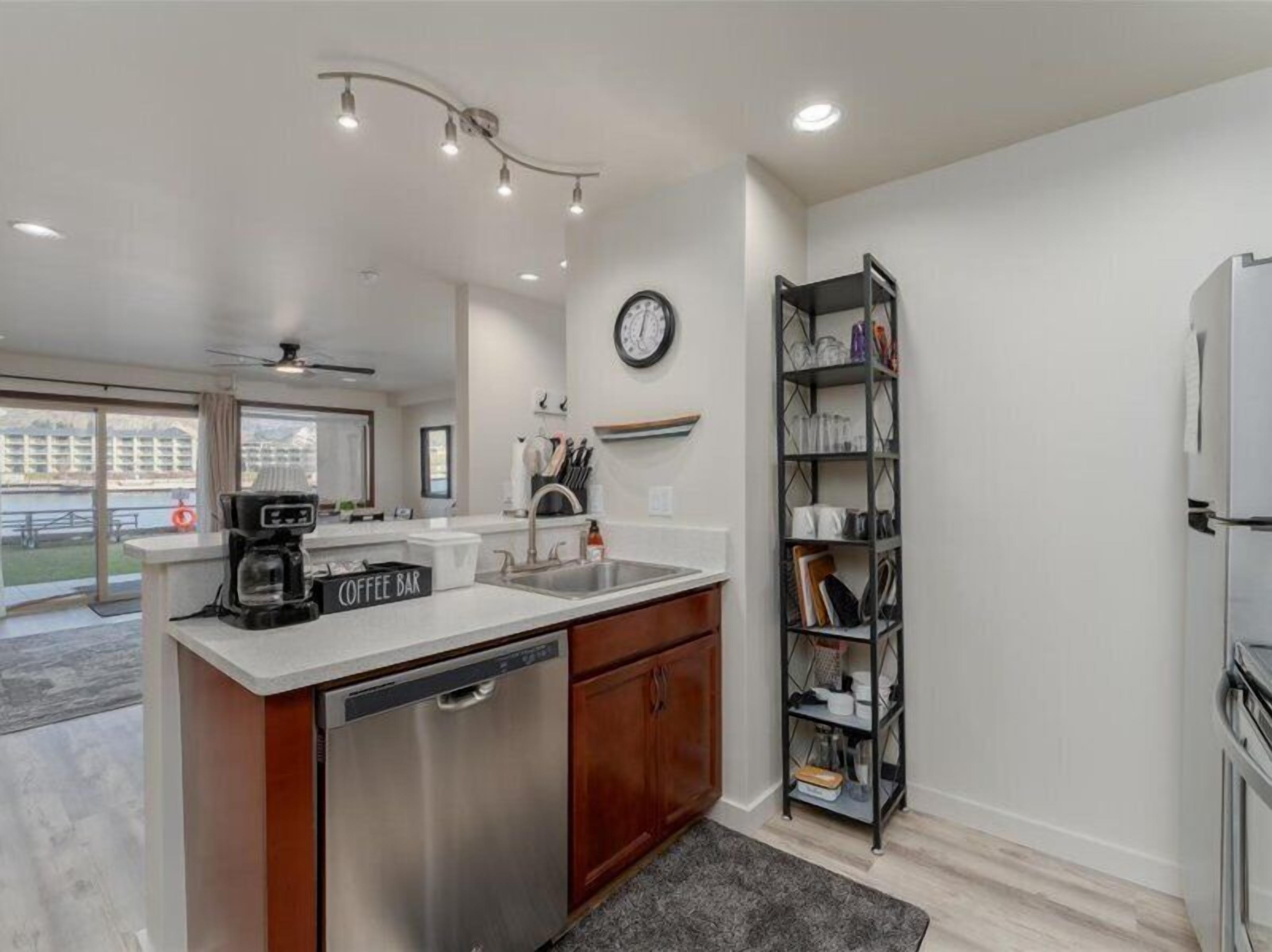 A modern kitchen with a coffee bar, dishwasher, and a clock on the wall.