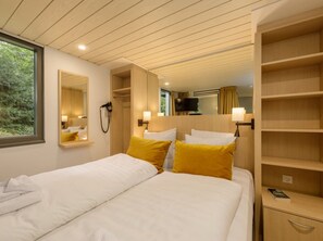A hotel room with two beds, wooden headboards, a large mirror, and a TV. - Hotel De Eemhof by Center Parcs (Zeewolde)