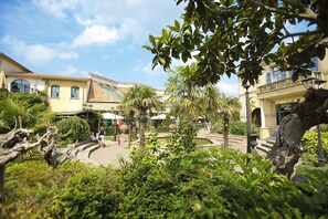 A courtyard with palm trees, a fountain, and a building with a tiled roof. - Hotel De Eemhof by Center Parcs (Zeewolde)