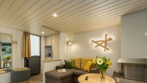 A modern living room with a sectional sofa, a round wooden coffee table, and a built-in fireplace. - Hotel De Eemhof by Center Parcs (Zeewolde)