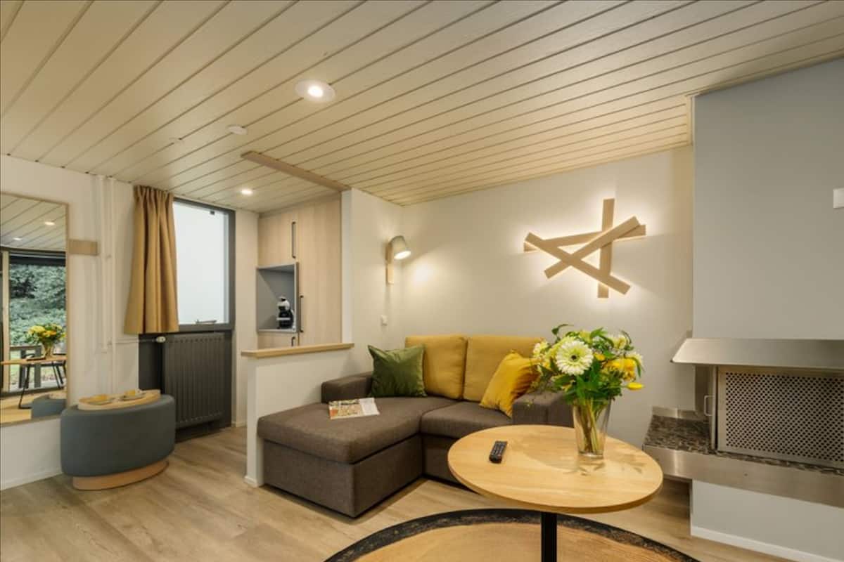 A modern living room with a sectional sofa, a round wooden coffee table, and a built-in fireplace.