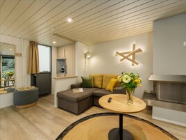 Una sala de estar moderna con un sofá modular, una mesa de centro redonda de madera y una chimenea empotrada.