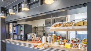 A breakfast bar with a coffee machine, refrigerator, and various food items. - B&B HOTEL Saint-Martin-de-Crau Alpilles Camargue (Saint-Martin-de-Crau)