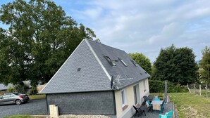 Ein kleines Haus mit geneigtem Dach, einer Satellitenschüssel und einem Schotterweg.