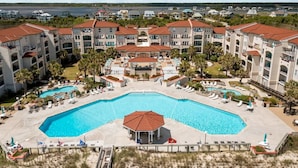A resort with a central swimming pool, multiple buildings with red-tiled roofs, and a view of the ocean. - Oceanfront 2BR condo at Villa Capriani 317A, North Topsail Beach, perfect for families. (North Topsail Beach)