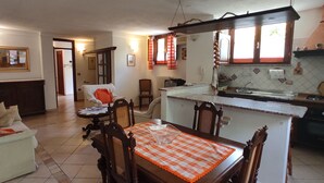 A compact living space with a dining area, kitchenette, and a sofa. - APARTMENT IN DORGALI, COMFORT AND RELAX GARDEN (Dorgali)