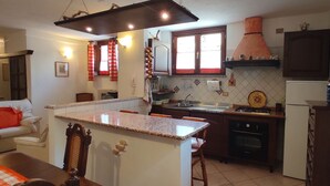 A kitchen with a granite countertop, wooden cabinets, a stove, and a refrigerator. - APARTMENT IN DORGALI, COMFORT AND RELAX GARDEN (Dorgali)