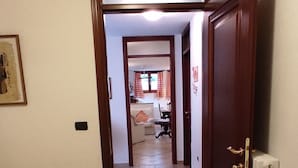 A hotel room with a bed, a radiator, and a hallway leading to a living area. - APARTMENT IN DORGALI, COMFORT AND RELAX GARDEN (Dorgali)