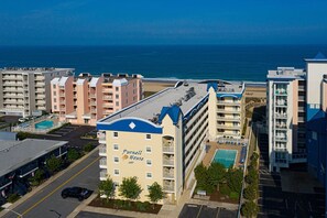 A multi-story hotel with a pool, located near a beach with a view of the ocean. - Modern 2BR / 2BA Oceanside Condo with Pool Midtown OC with free WIFI (Ocean City)