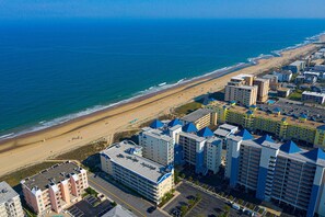Een kusthotel met meerdere gebouwen, een strand en een parkeerplaats.