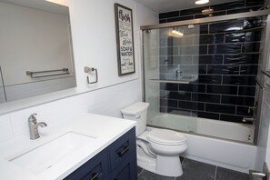 Un baño moderno con un lavamanos blanco, un inodoro y una ducha con mampara de vidrio.