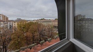 Une vue depuis une fenêtre donnant sur un paysage urbain, avec des bâtiments et des arbres.
