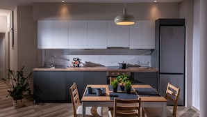 A modern kitchen with grey cabinets, a wooden countertop, a built-in oven, and a stainless steel refrigerator. - Archipelagos Apt with Unique Sea & Old Port View in the City Center (Heraklion)