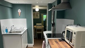 A compact kitchen with a microwave, sink, and wooden countertop.