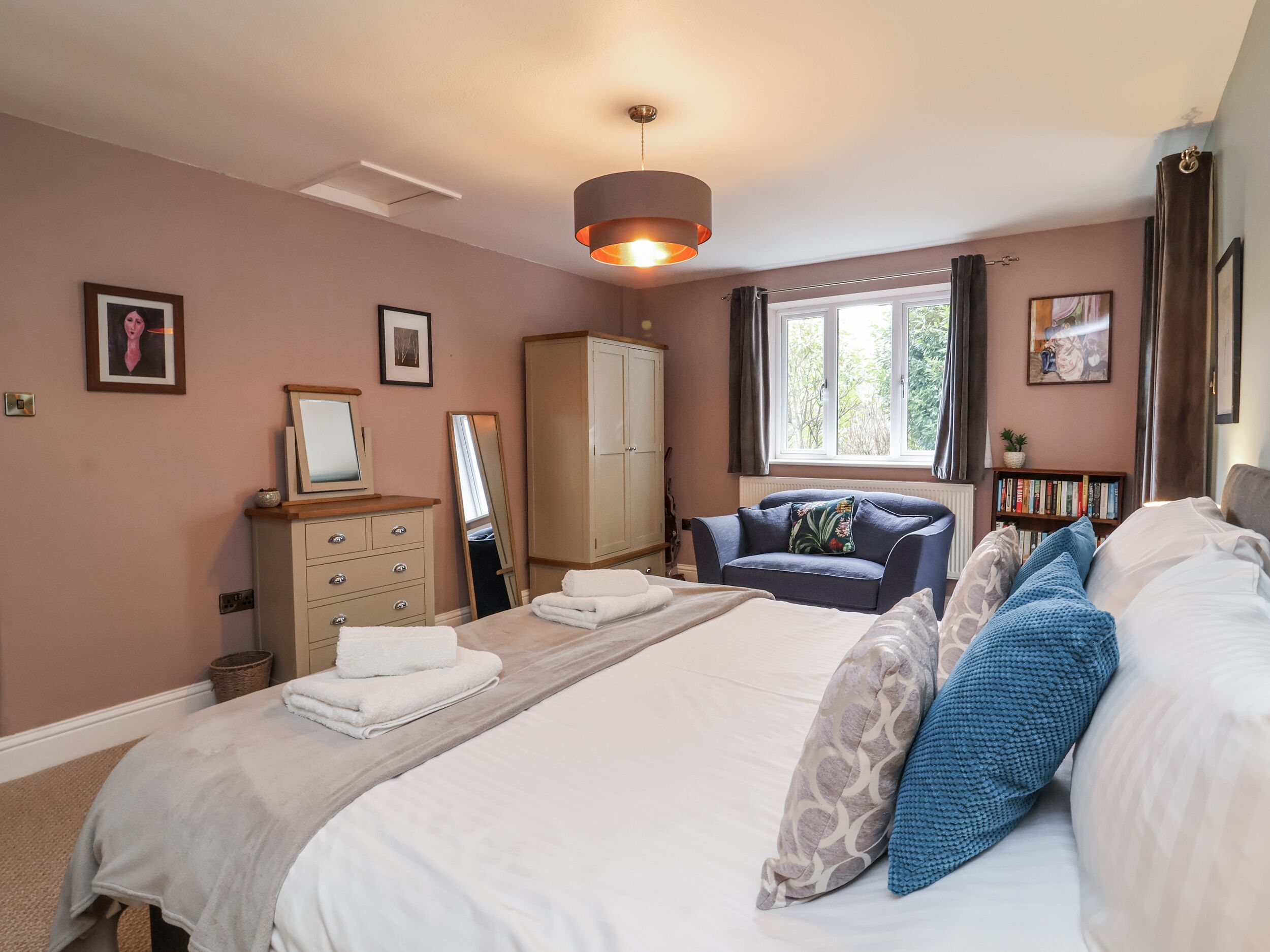 Une chambre à coucher comprenant un lit, une commode, une armoire, une chaise, une fenêtre et une bibliothèque.