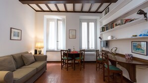 Una sala de estar acogedora con un sofá, una mesa de comedor con sillas y una zona de cocina con mostrador y estanterías.
