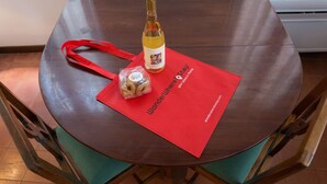 Una mesa de madera con un mantel individual rojo, una botella de vino y una pequeña bolsa de aperitivos.