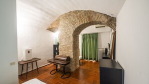 A room with a stone archway, a radiator, a bench, and a table with towels. - Campo de Fiori Grotto Apartment (Roma)