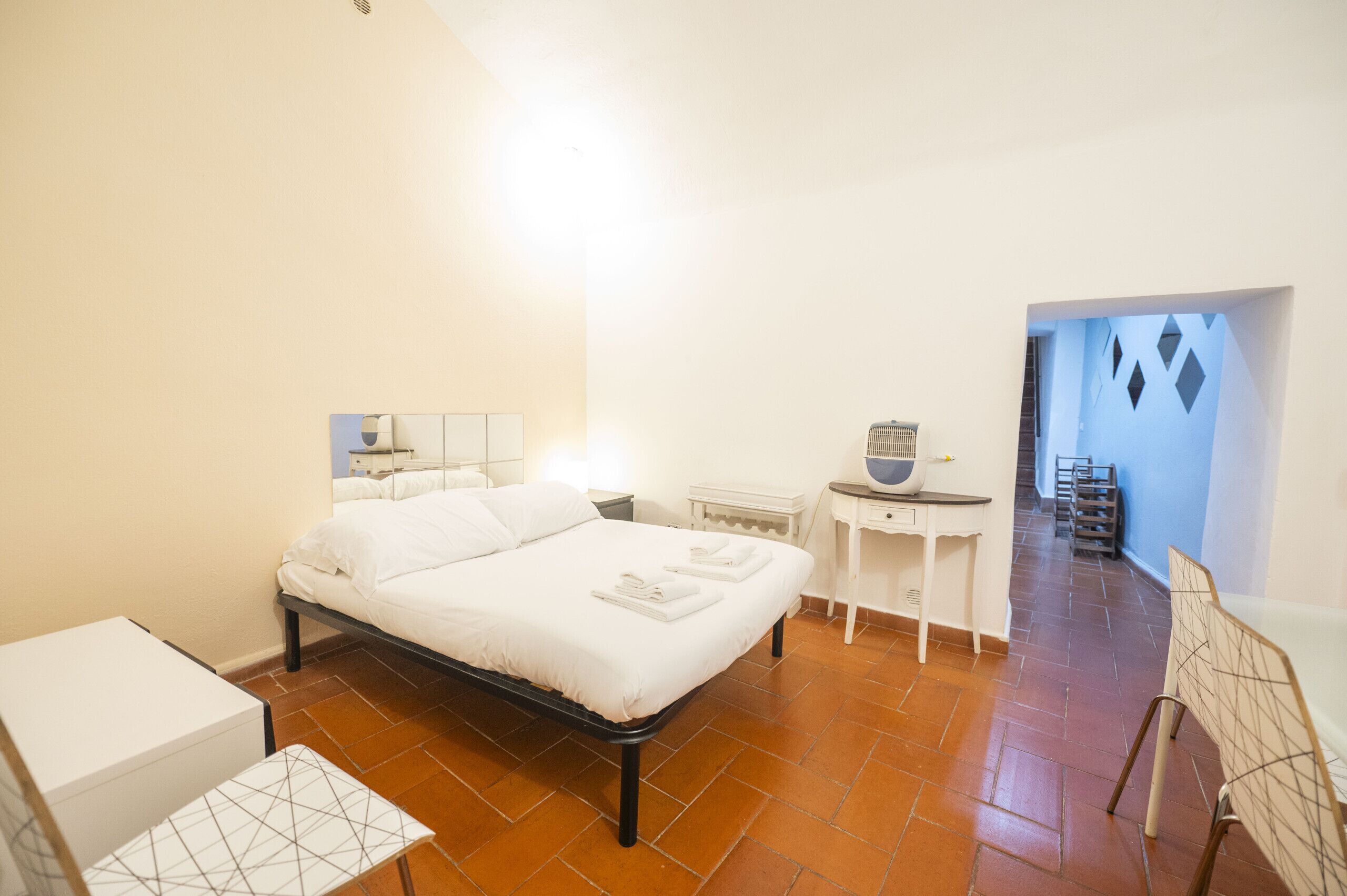 A bedroom with a bed, bedside tables, a small table with a bowl, and a chair.