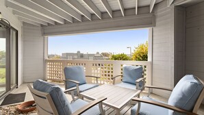 A covered patio with a table and four chairs, a lattice fence, and a view of buildings and trees. - Vista Pacific- Del Mar Rental with Ocean Views, Pool, A/C & Walkable Dining (Del Mar)