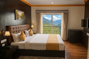A hotel room with a large bed, a television, a desk with a telephone, and a window with a mountain view. - HOTEL YEASEL CONTINENTAL (Gangtok)