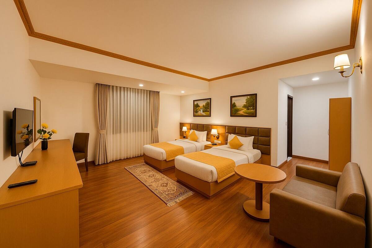 A hotel room with two beds, a desk, a chair, a small table, and a TV.