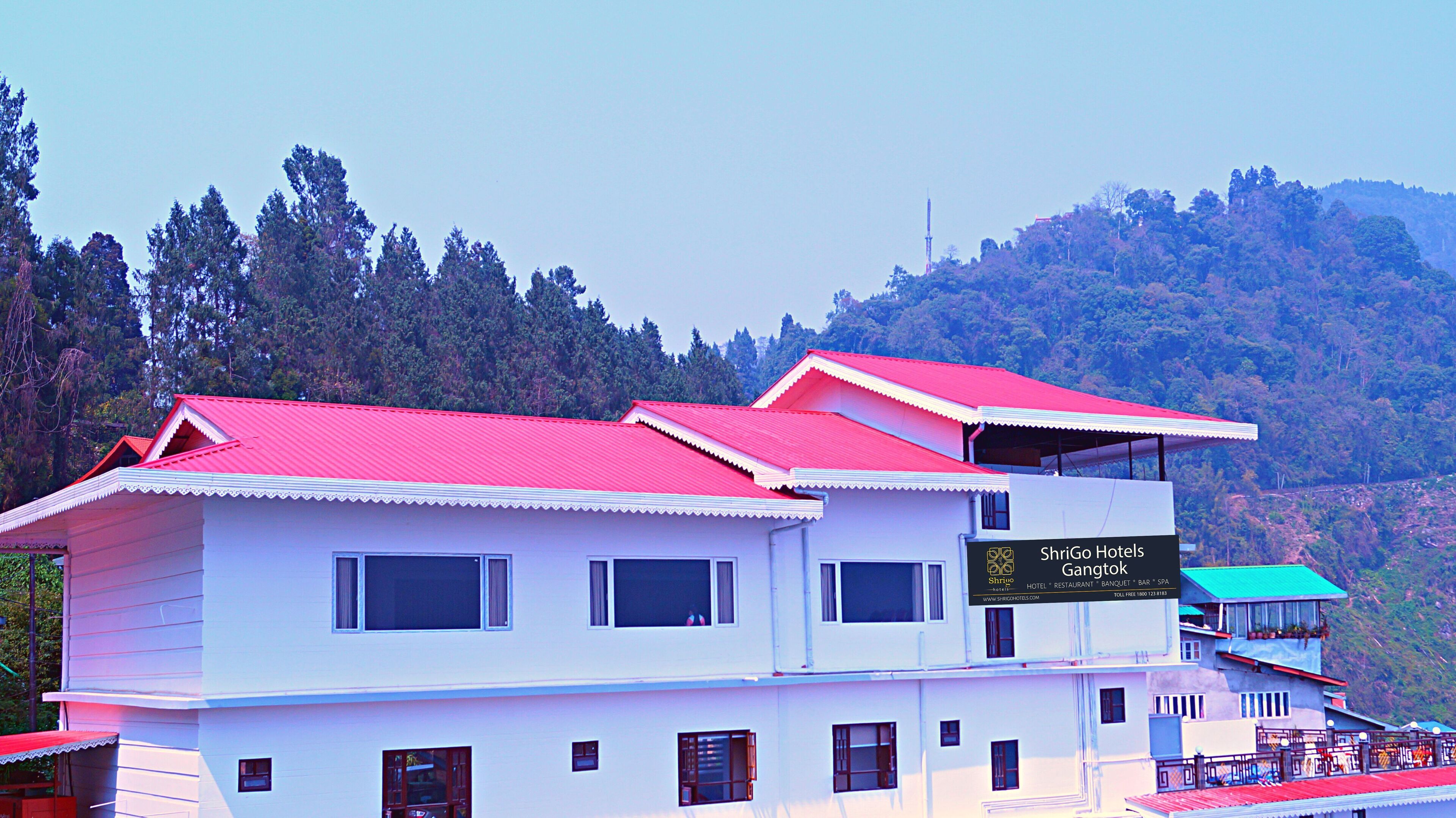 A two-story building with a red roof and white walls, labeled as ShriGo Hotels Gangtok.