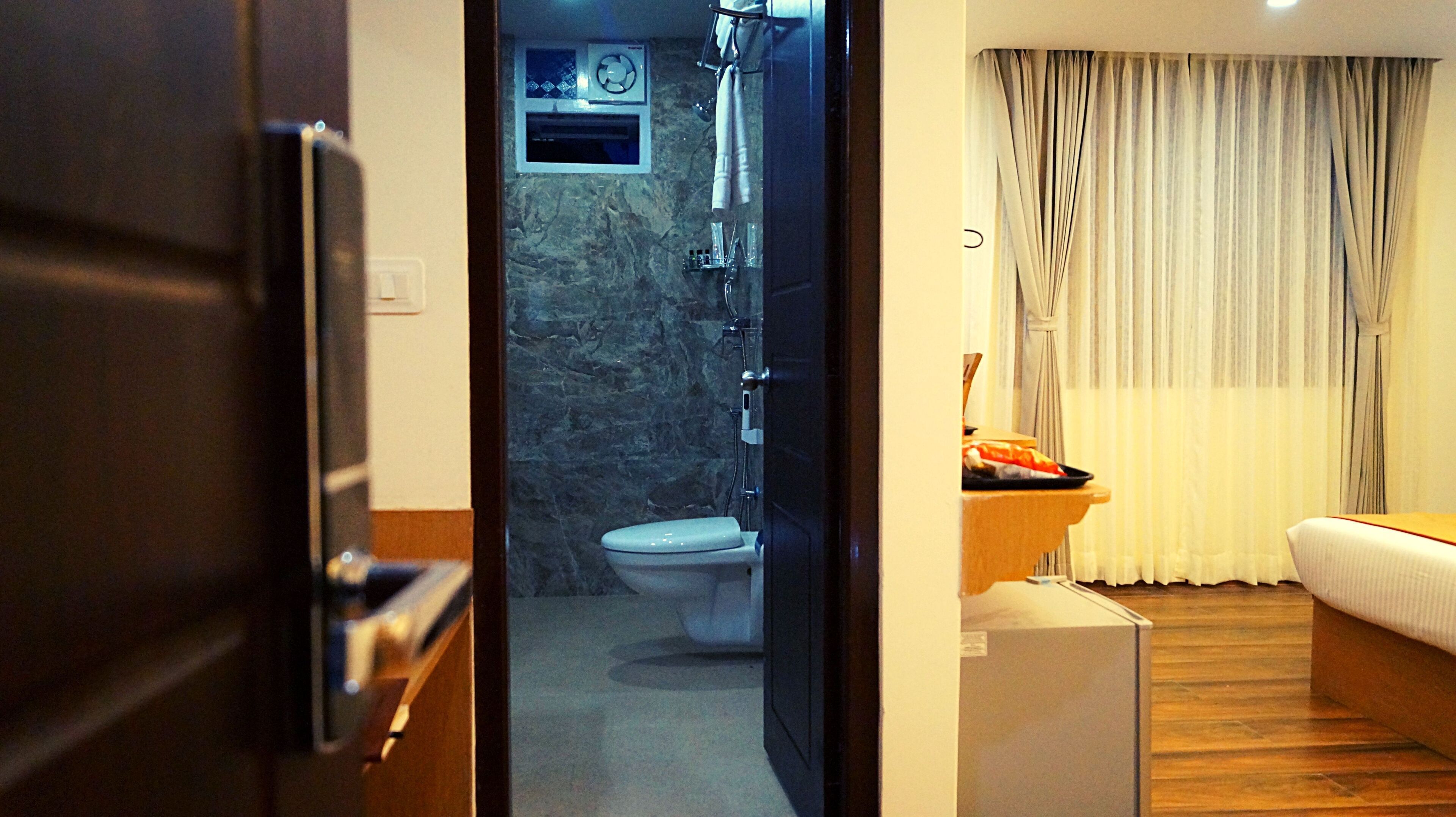 Un baño de hotel con inodoro, ducha y una ventana pequeña.