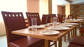 A dining area with wooden tables and brown upholstered chairs.