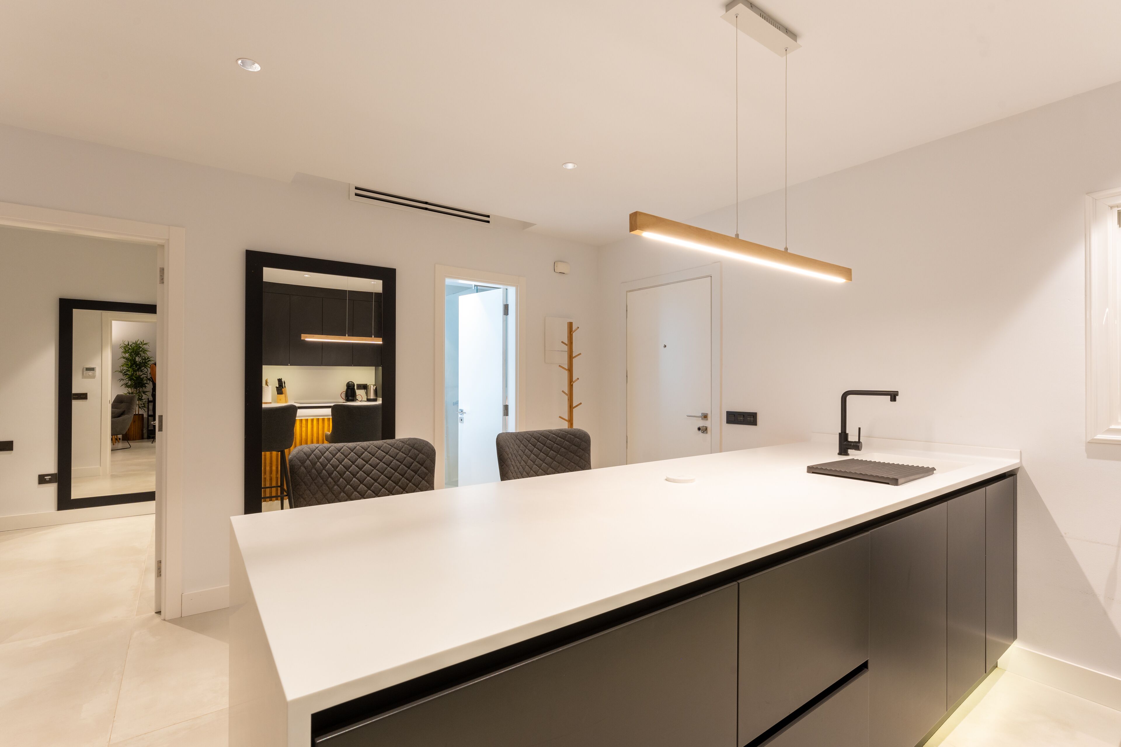 A modern kitchen with a white countertop, dark cabinets, and a pendant light.