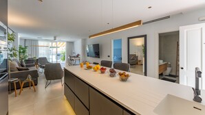 Una cucina moderna con un lungo bancone, un lavello e una zona pranzo con sedie e tavolo.