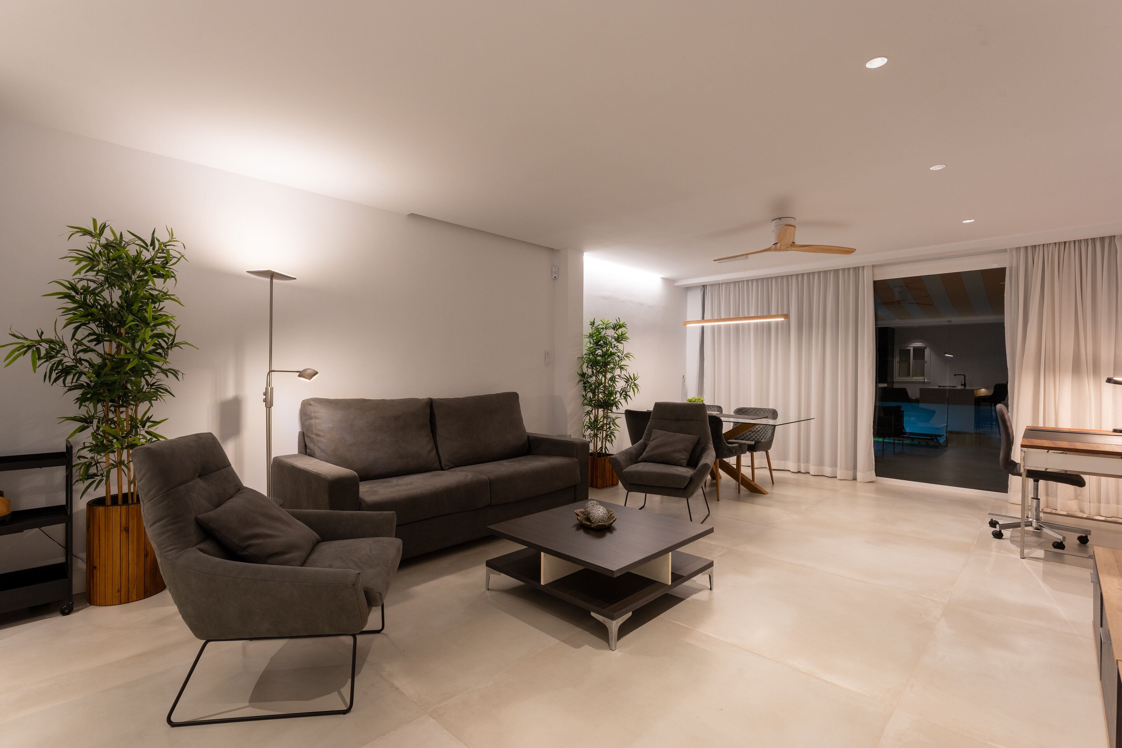 Una sala moderna con un sofá, sillones, una mesita de centro y un comedor con mesa y sillas.