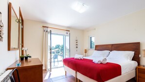 Ein Schlafzimmer mit Bett, Schreibtisch, Stuhl, Fenster und Balkon.
