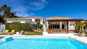 Ein Poolbereich mit klarem, blauem Pool, gelben Liegestühlen und einer überdachten Terrasse mit Sitzgelegenheiten.