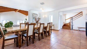 Ein geräumiger Essbereich mit Holztisch und -stühlen, einer Treppe und Blick ins Freie.
