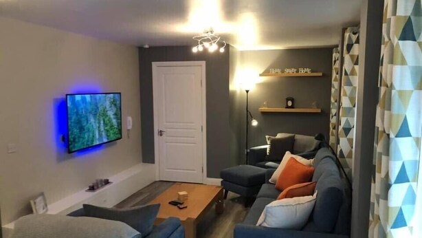 Una sala de estar moderna con un sofá, una mesa de centro y un televisor de pantalla plana montado en la pared.