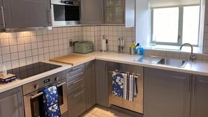 Cocina moderna con armarios grises, horno empotrado, microondas, tostadora y ventana con un lavamanos.