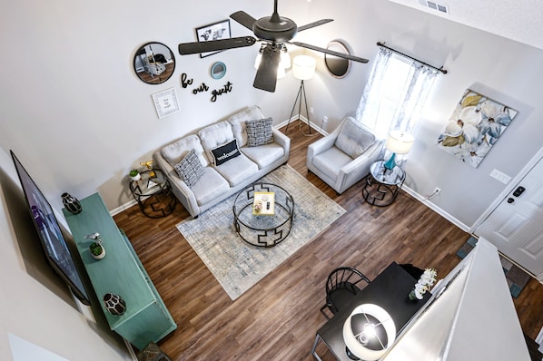 A modern living room with a sofa set, a coffee table, a TV, and a ceiling fan.